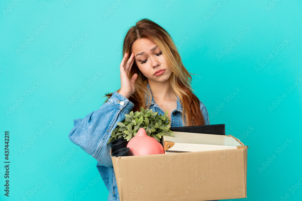Teenager blonde girl making a move while picking up a box full of things with headache Teenager blonde girl making a move while picking up a box full of things with headache