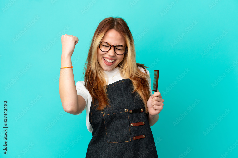 Young hairdresser girl over isolated blue background celebrating a victory Young hairdresser girl over isolated blue background celebrating a victory