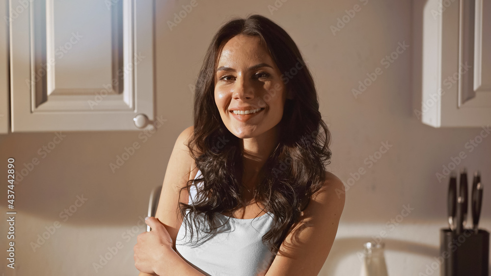 happy woman smiling while looking at camera in kitchen happy woman smiling while looking at camera in kitchen