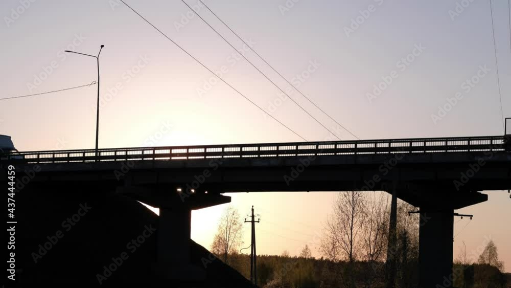 Silhouette of container truck and other cars driving on the highway bridge on background sunset. 4k. Cargo transportation or trucking industry concept. Silhouette of container truck and other cars driving on the highway bridge on background sunset. 4k. Cargo transportation or trucking industry concept.