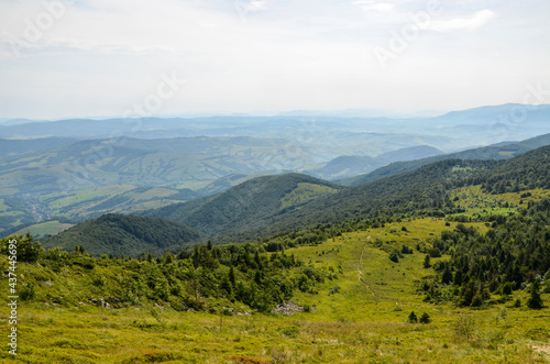 A view from the mountain ridge down to the meadow and forest hills. Carpathian mountains  Ukraine. Silence and harmony of nature.