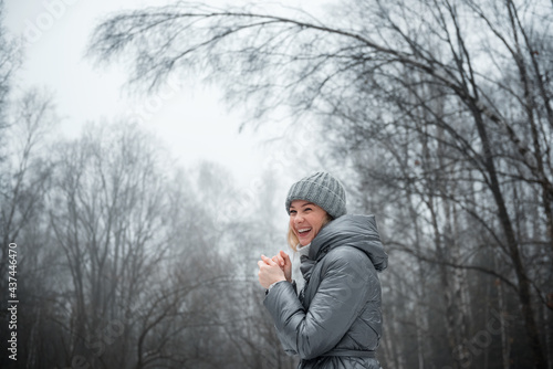 Girl in a raincoat on the background of the forest in the snow