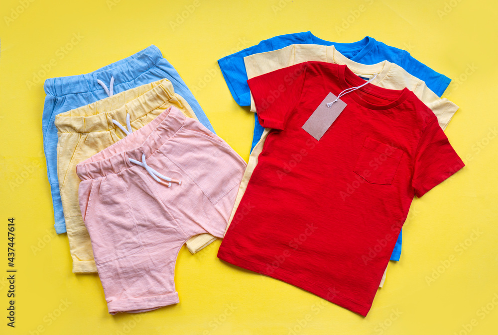 Children's T-shirts and shorts lie on yellow background