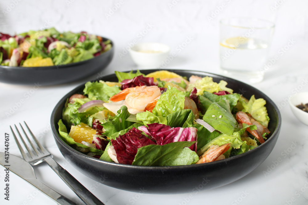 Grilled shrimp, lettuce, orange, red onion on a white plate, close-up. Fried shrimps. Healthy salad. Fresh summer salad with shrimps and a mix of green leaves. Fresh seafood recipe. Grilled shrimp, lettuce, orange, red onion on a white plate, close-up. Fried shrimps. Healthy salad. Fresh summer salad with shrimps and a mix of green leaves. Fresh seafood recipe.