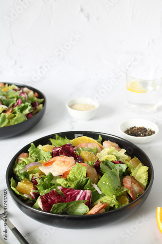 Italian shrimp salad with oranges, red onions, green lettuce, olive oil and sesame seeds. Green mix salad with shrimps, oranges, olive oil and sesame seeds, vertical photo copy space