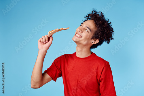 happy guy with slice of pizza on blue background curly hair emotions cropped view