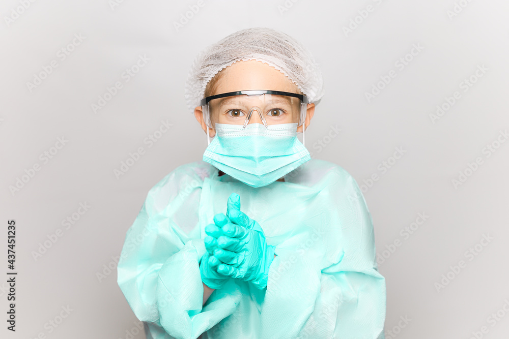 a boy in a medical gown and mask clasped his gloved hands together a boy in a medical gown and mask clasped his gloved hands together