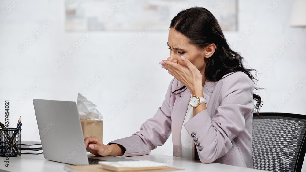 brunette businesswoman with allergy and running nose near laptop on desk brunette businesswoman with allergy and running nose near laptop on desk
