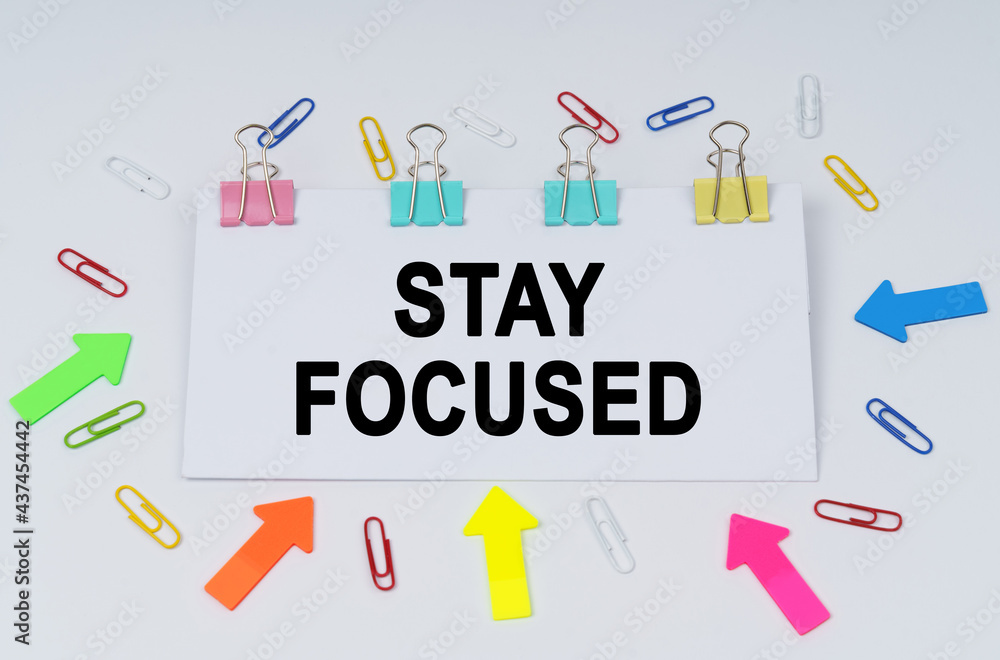 On the table there are paper clips and directional arrows, a sign that says - STAY FOCUSED On the table there are paper clips and directional arrows, a sign that says - STAY FOCUSED
