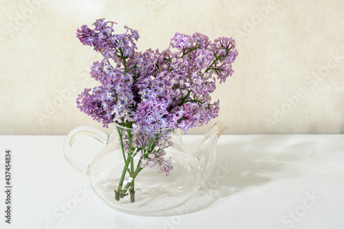 Wallpaper Mural composition of a bouquet of lilacs in a glass teapot on a white table on a beige background Torontodigital.ca