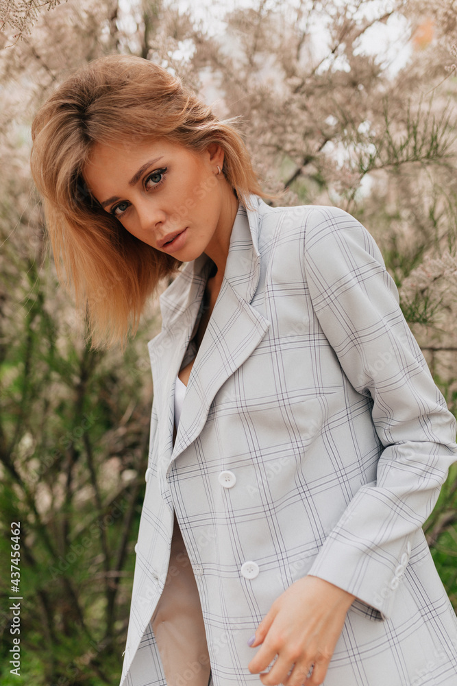 Fashion stylish lady with loose hair wearing light jacket looking at camera while posing outdoor in the city Fashion stylish lady with loose hair wearing light jacket looking at camera while posing outdoor in the city