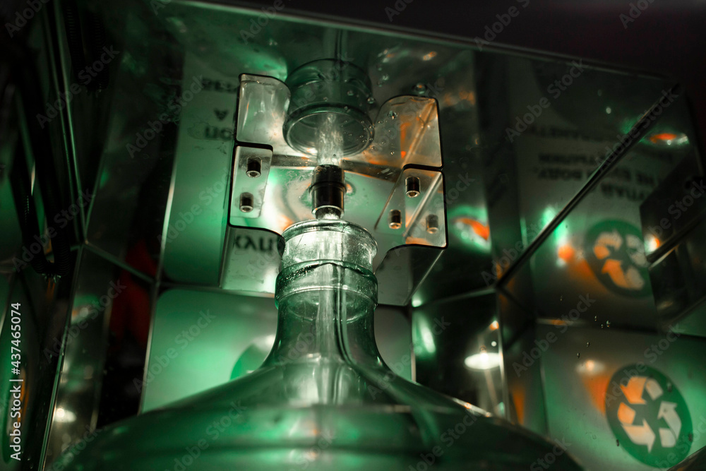 pouring pure fresh water into a pet bottle in a vending machine, the foreground and background are blurred with bokeh effect pouring pure fresh water into a pet bottle in a vending machine, the foreground and background are blurred with bokeh effect