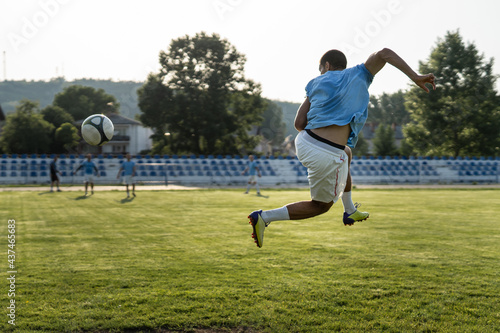 Full length soccer football player kicking the ball on game or training