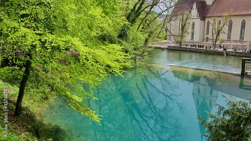 Scenic view of a Catholic monastery in the village of Blaubeuren, Germany. A Catholic monastery and the surrounding trees are reflecting in the turqoise-blue colored water. photo