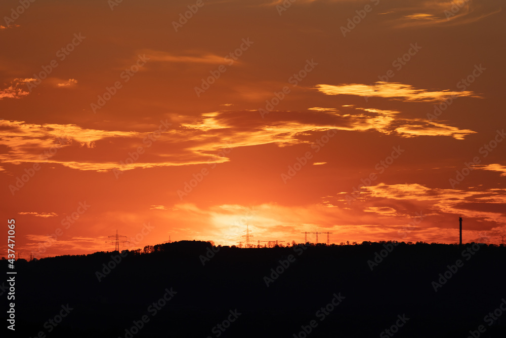 silhouette of high voltage power lines and pylons against a beautiful sunset - beautiful clouds on the sunset sky
