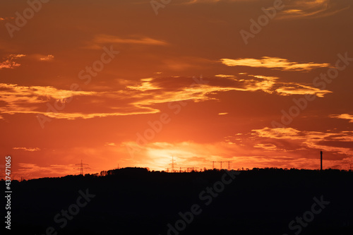 silhouette of high voltage power lines and pylons against a beautiful sunset - beautiful clouds on the sunset sky 