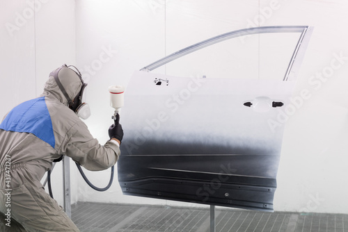 Foto a worker in a gray protective suit are painting car door parts  spray