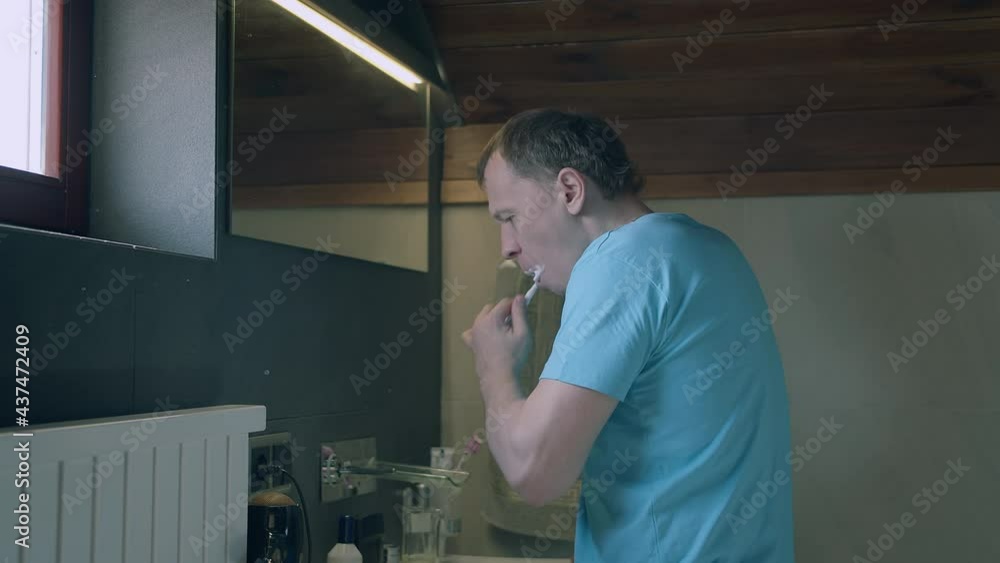 Man brushing teeth in the morning while standing in the bathroom Man brushing teeth in the morning while standing in the bathroom