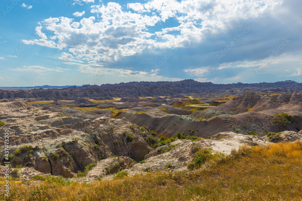 Badlands landscape with sunbeam and dry grass in summer, Badlands national park, South Dakota, USA.