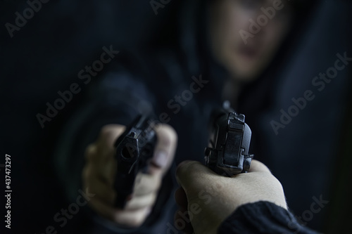 Two shooters threaten each other with weapons. First-person view of hand with pistol pointed at guy in hoody with revolver. Criminal and detective. Killer and cop.
