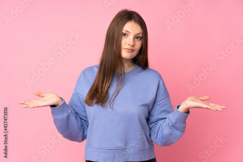 Teenager caucasian girl isolated on pink background having doubts