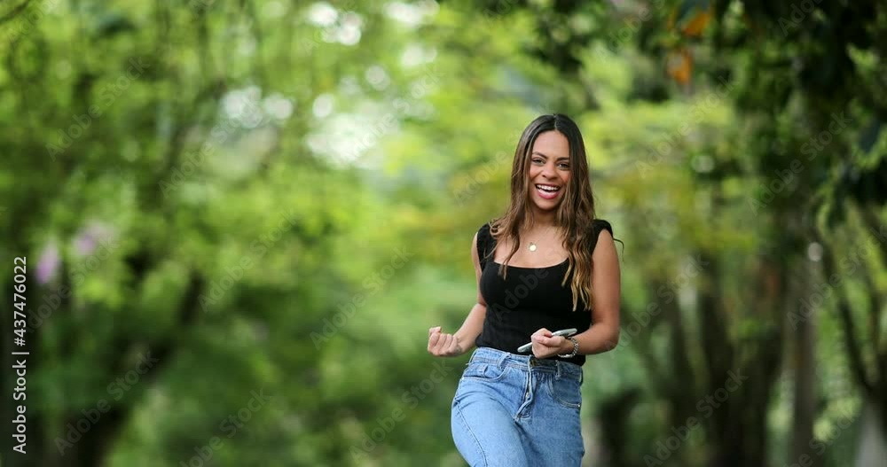 Pretty girl happy with message on phone jumping with joy Pretty girl happy with message on phone jumping with joy