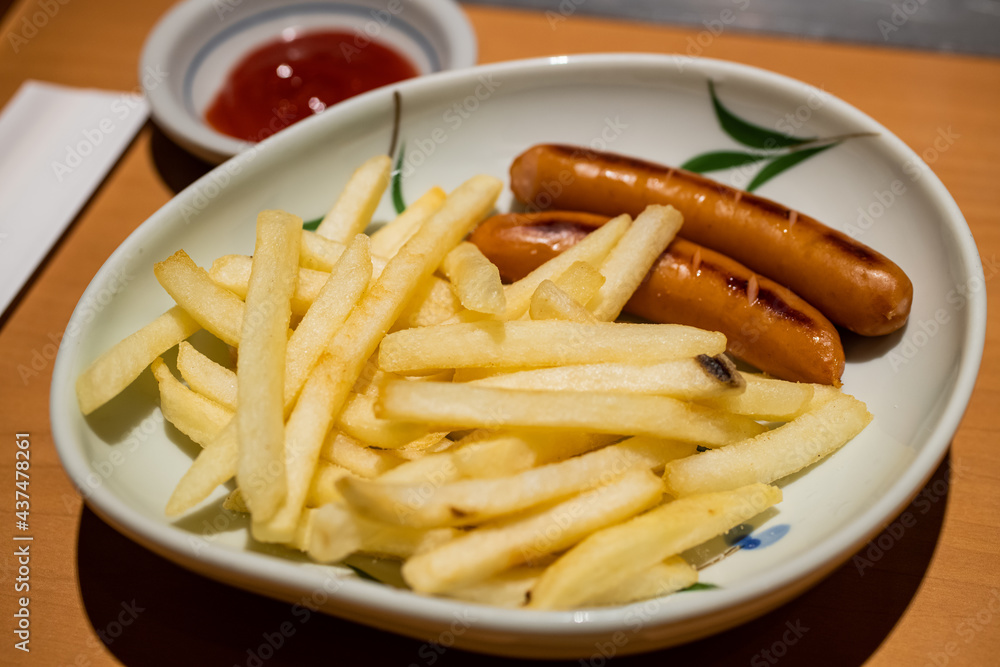 Close-up of french fries with grilled sausage serving as appetiser on the dish dipping with tomato sauce. Close-up of french fries with grilled sausage serving as appetiser on the dish dipping with tomato sauce.