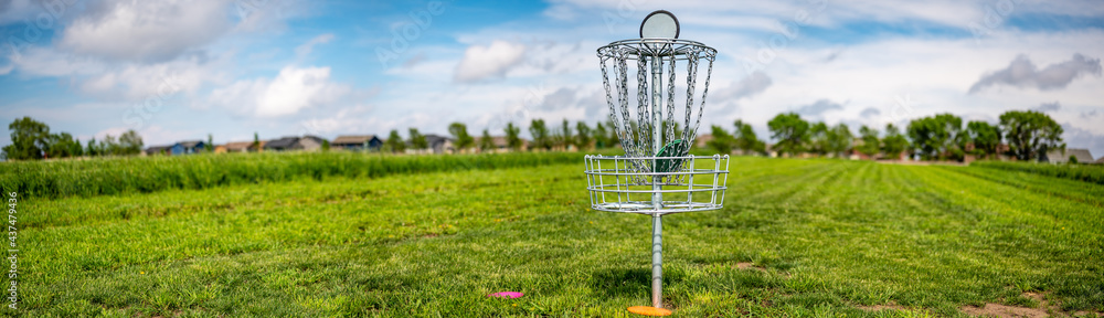 Panoramic view across an open grass disc golf course with a chain goal Panoramic view across an open grass disc golf course with a chain goal