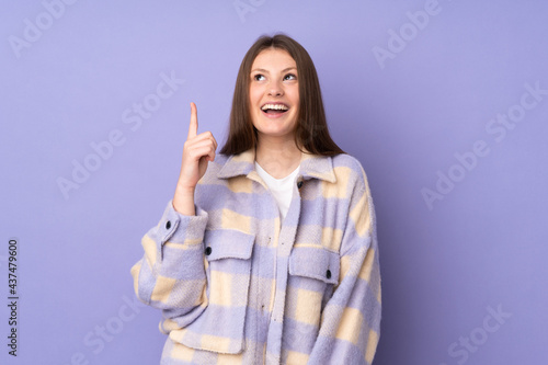 Teenager caucasian girl isolated on purple background pointing up and surprised