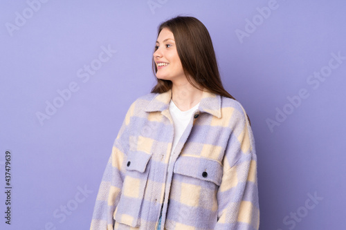 Teenager caucasian girl isolated on purple background looking to the side and smiling © luismolinero