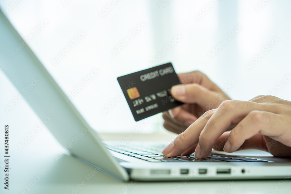 Unrecognizable Asian young man using a credit card for making a purchase on the internet. Unrecognizable Asian young man using a credit card for making a purchase on the internet.