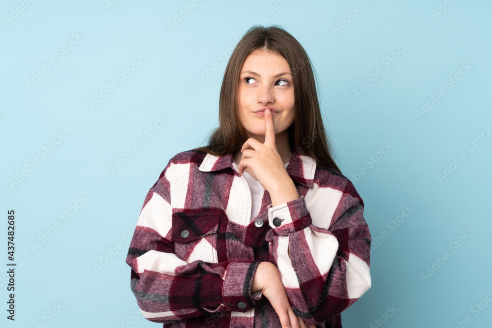 Teenager caucasian girl isolated on blue background having doubts while looking up Teenager caucasian girl isolated on blue background having doubts while looking up