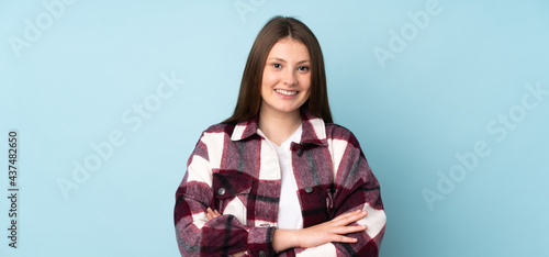 Teenager caucasian girl isolated on blue background keeping the arms crossed in frontal position