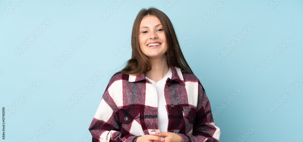 Teenager caucasian girl isolated on blue background laughing