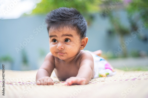 Crawling sweet baby girl in a reed mat looking forward uninterestingly. facial expressions of five months old cute crawling baby front view close-up portraiture photo. photo