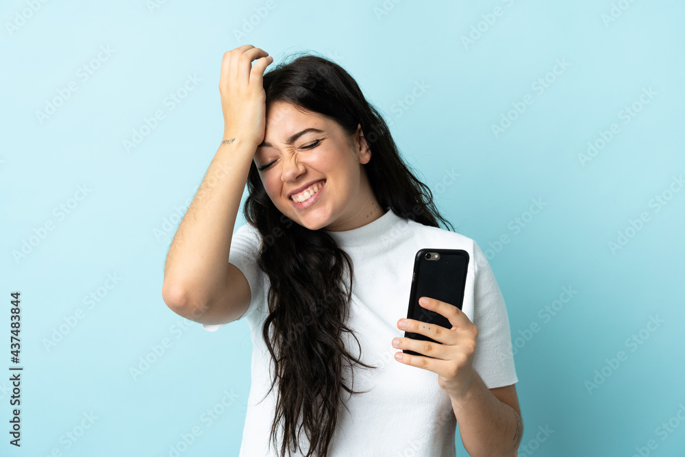 Young woman using mobile phone isolated on blue background has realized something and intending the solution Young woman using mobile phone isolated on blue background has realized something and intending the solution
