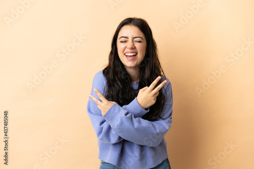 Young caucasian woman over isolated background smiling and showing victory sign © luismolinero