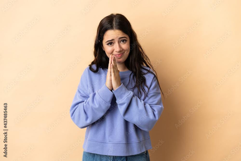 Young caucasian woman over isolated background keeps palm together. Person asks for something Young caucasian woman over isolated background keeps palm together. Person asks for something