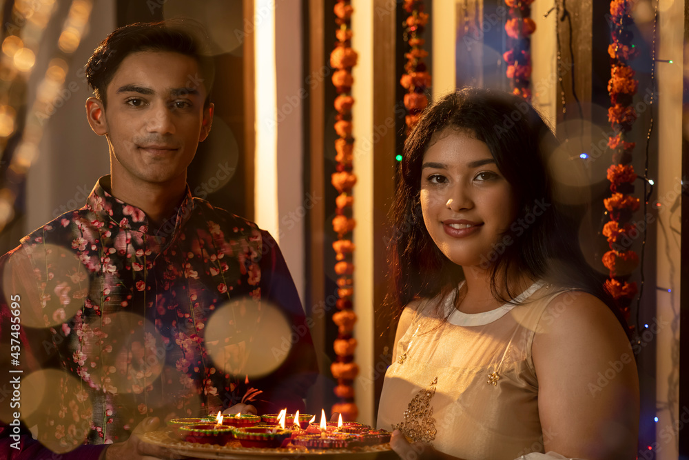 Portrait of an Indian man and woman lighting diyas and lamps on the festive occasion of Diwali. Celebrations at home. Portrait of an Indian man and woman lighting diyas and lamps on the festive occasion of Diwali. Celebrations at home.