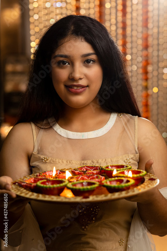 Portrait of an Indian woman holding diyas and lamps on the festive occasion of Diwali. Celebrations at home