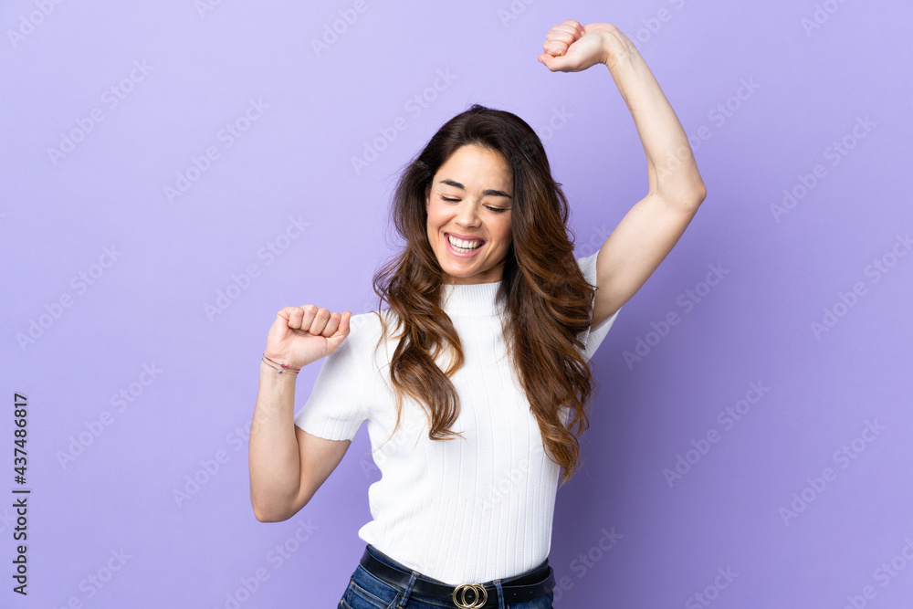 Woman over isolated purple background celebrating a victory Woman over isolated purple background celebrating a victory