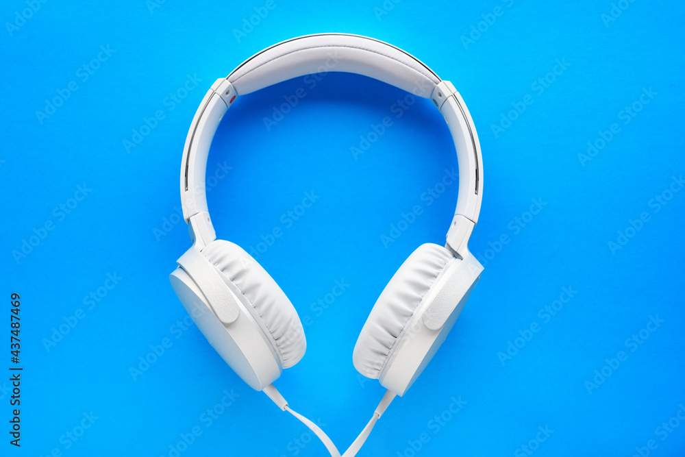 White wired Headphones on a blue background. Entertainment concept. White wired Headphones on a blue background. Entertainment concept.