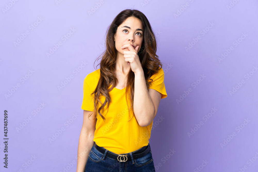 Woman over isolated purple background having doubts and with confuse face expression Woman over isolated purple background having doubts and with confuse face expression