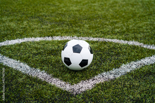 classic pentagonal black and white ball on football or soccer field with artificial grass © MasterSergeant
