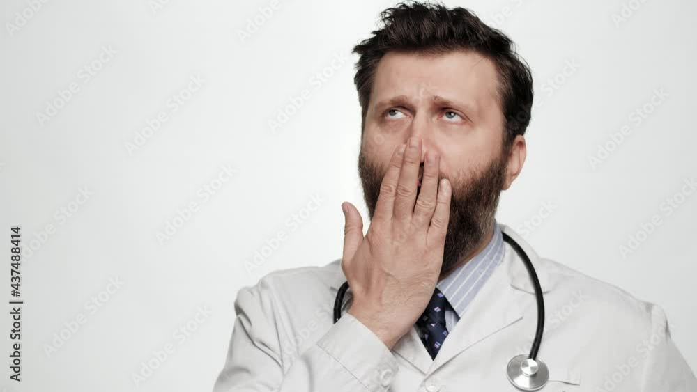 Doctor yawns. Portrait of tired bored man doctor on white background yawns and covers his mouth with hand Doctor yawns. Portrait of tired bored man doctor on white background yawns and covers his mouth with hand