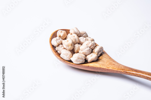 a spoon of dried chickpeas against white background