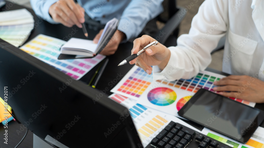 graphic designer team working on web design using color swatches editing artwork using tablet and a stylus at desks In creative office graphic designer team working on web design using color swatches editing artwork using tablet and a stylus at desks In creative office