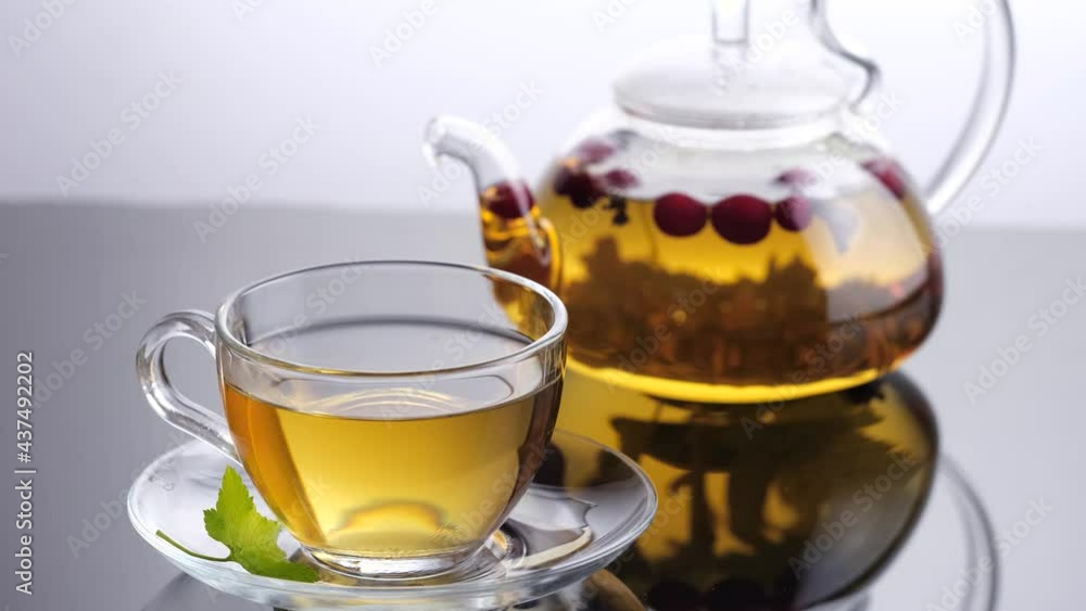 Static view of glass teapot and cup of Hot herbal tea with red crandberries Static view of glass teapot and cup of Hot herbal tea with red crandberries