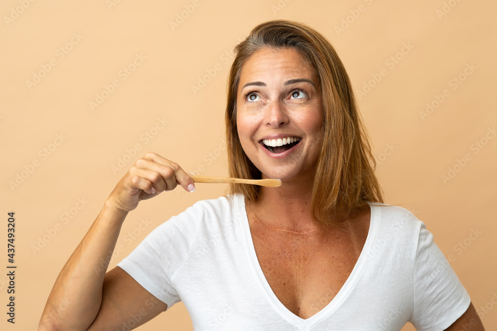 Middle age brazilian woman isolated on beige background with a toothbrush Middle age brazilian woman isolated on beige background with a toothbrush