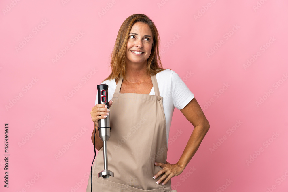 Middle age woman using hand blender isolated on pink background thinking an idea while looking up Middle age woman using hand blender isolated on pink background thinking an idea while looking up